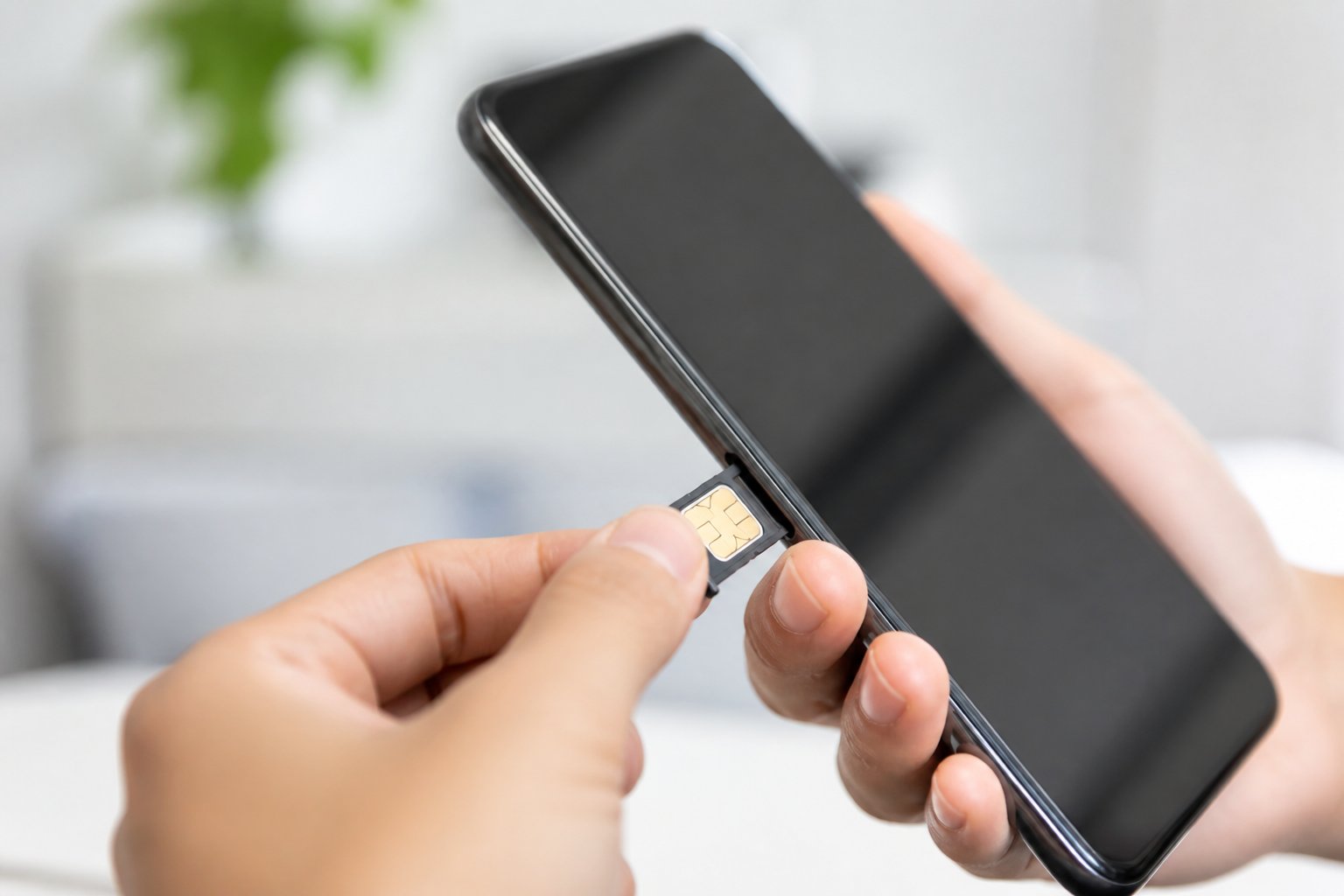 Mão segurando um smartphone com o compartimento do chip parcialmente aberto, mostrando um chip sendo inserido.